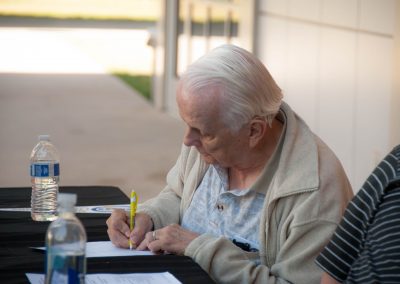 Ron Underwood writing at a table during the California High School Speech Association State Championship, reflecting his lifelong commitment to service and excellence.